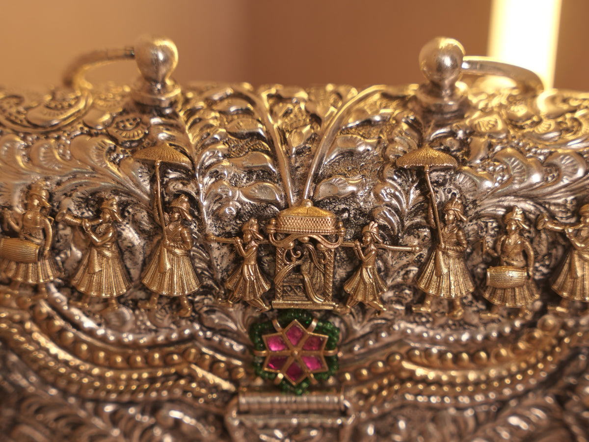 Close view of the purse flap, showing drummers and umbrella bearers walking beside the palanquin.