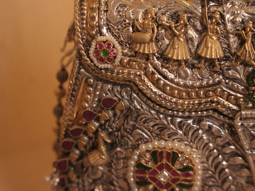 Side of the silver purse, with teardrop red stones, gold-tone birds and the bead chain strap.