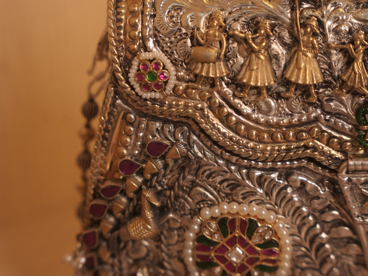 Side of the silver purse, with teardrop red stones, gold-tone birds and the bead chain strap.
