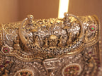 Corner of the purse showing the gold-tone beaded borders and a stone set floral medallion.
