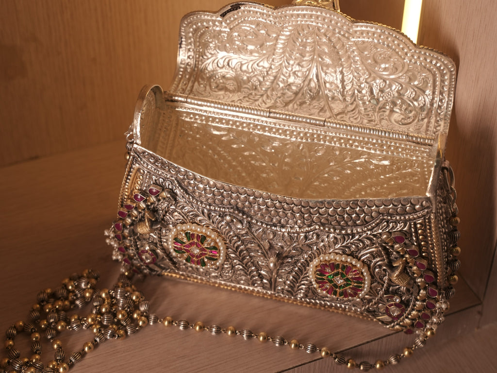 The purse open on its hinge, showing the fully engraved silver interior.