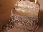 The purse open on its hinge, showing the fully engraved silver interior.