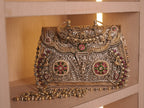 The baraat purse on a shelf with its detachable chain of fluted silver and gold-tone beads.