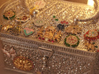 Close view of the lid charms, including the palanquin group and a red stone set bar.
