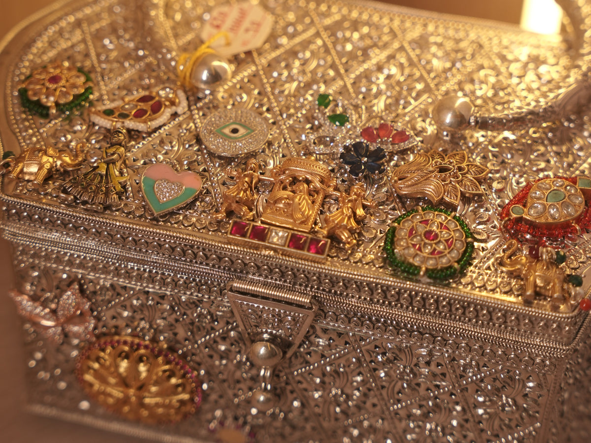 Close view of the lid charms, including the palanquin group and a red stone set bar.