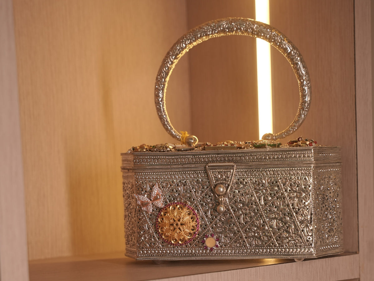 The filigree box purse standing on a shelf with its oval handle upright.