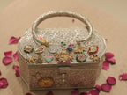 The charm studded box purse on a table scattered with rose petals.