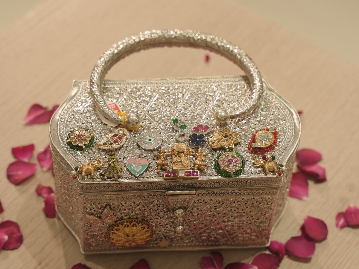 The charm studded box purse on a table scattered with rose petals.