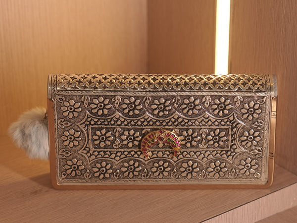 Front of the oxidised silver clutch wallet, chased with flower heads around a meena work crescent of pink and green stones.