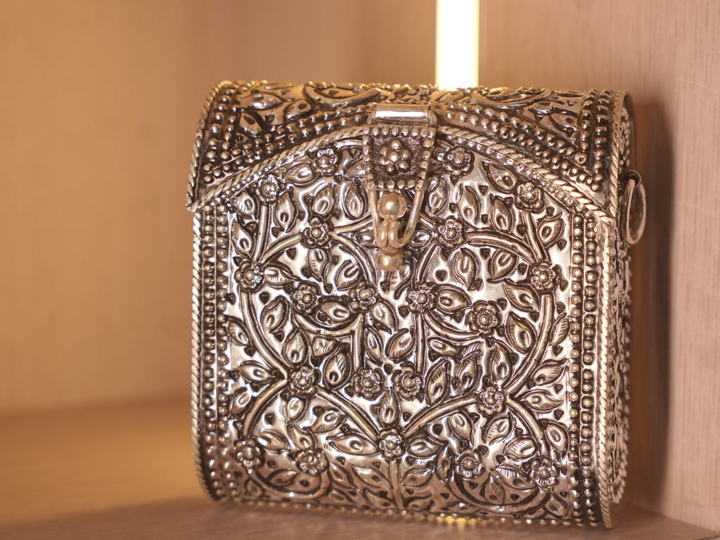 Front of the oxidised silver box bag, worked with a repousse vine of flowers and leaves inside beaded borders.