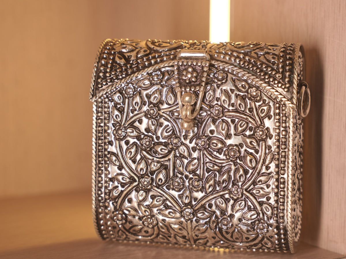 Front of the oxidised silver box bag, worked with a repousse vine of flowers and leaves inside beaded borders.