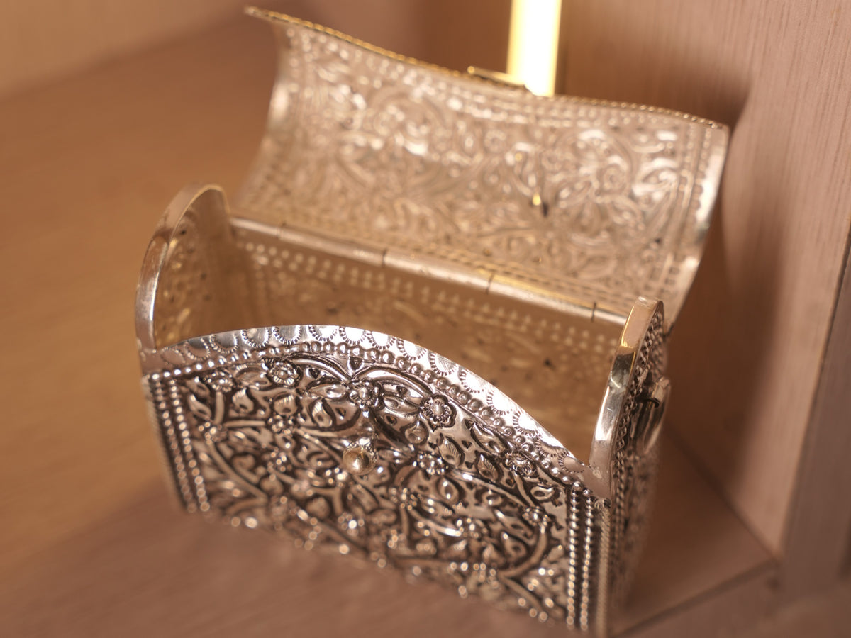 The oxidised box bag open on its hinge, showing the polished interior behind the floral front.