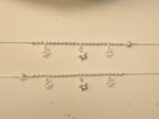 Close view of the clover and star charms hanging below the rice beads on the silver payal.
