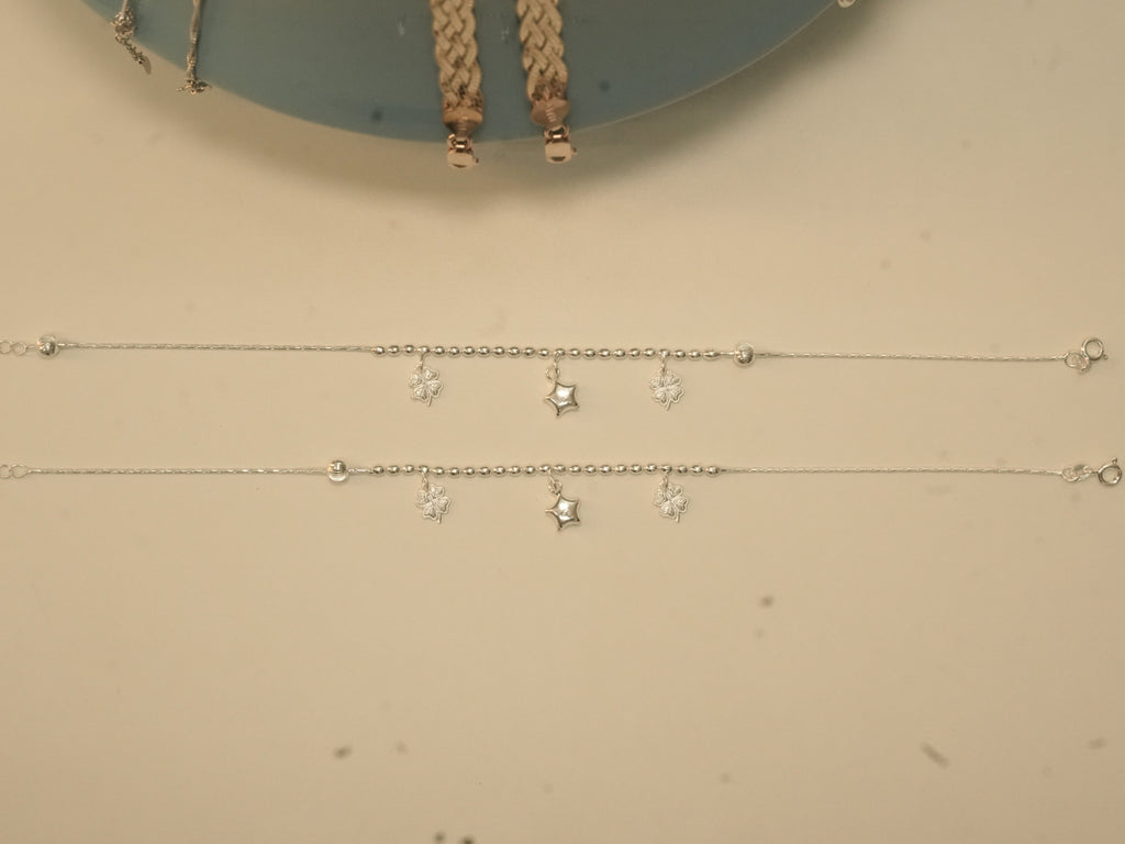 The pair of clover and star payal laid out full length, showing the spring ring clasps.