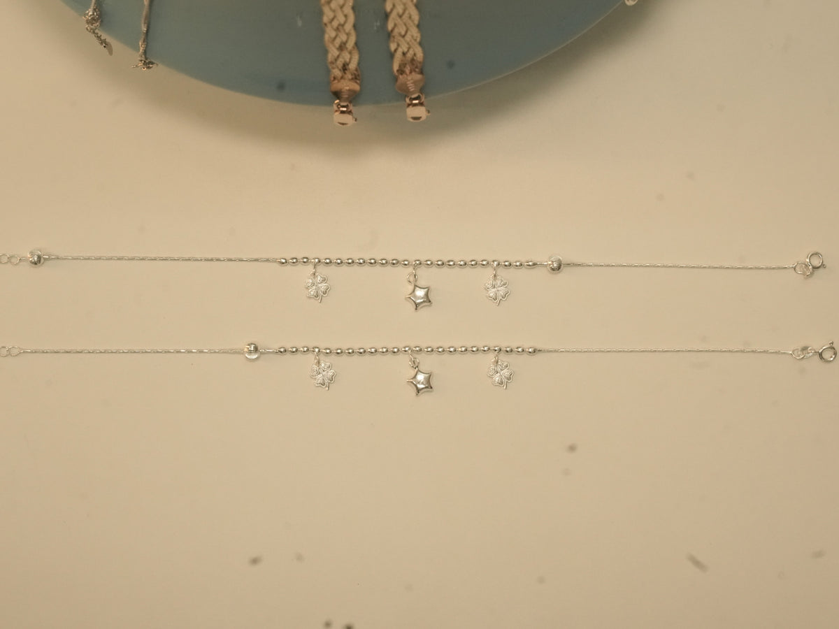 The pair of clover and star payal laid out full length, showing the spring ring clasps.