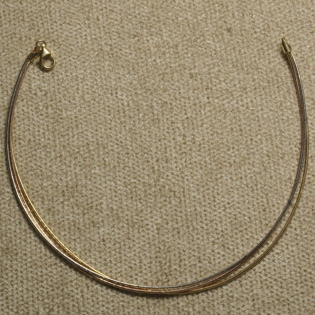 Sterling silver anklet with gold-tone and rose gold-tone strands photographed from above on textured cloth.