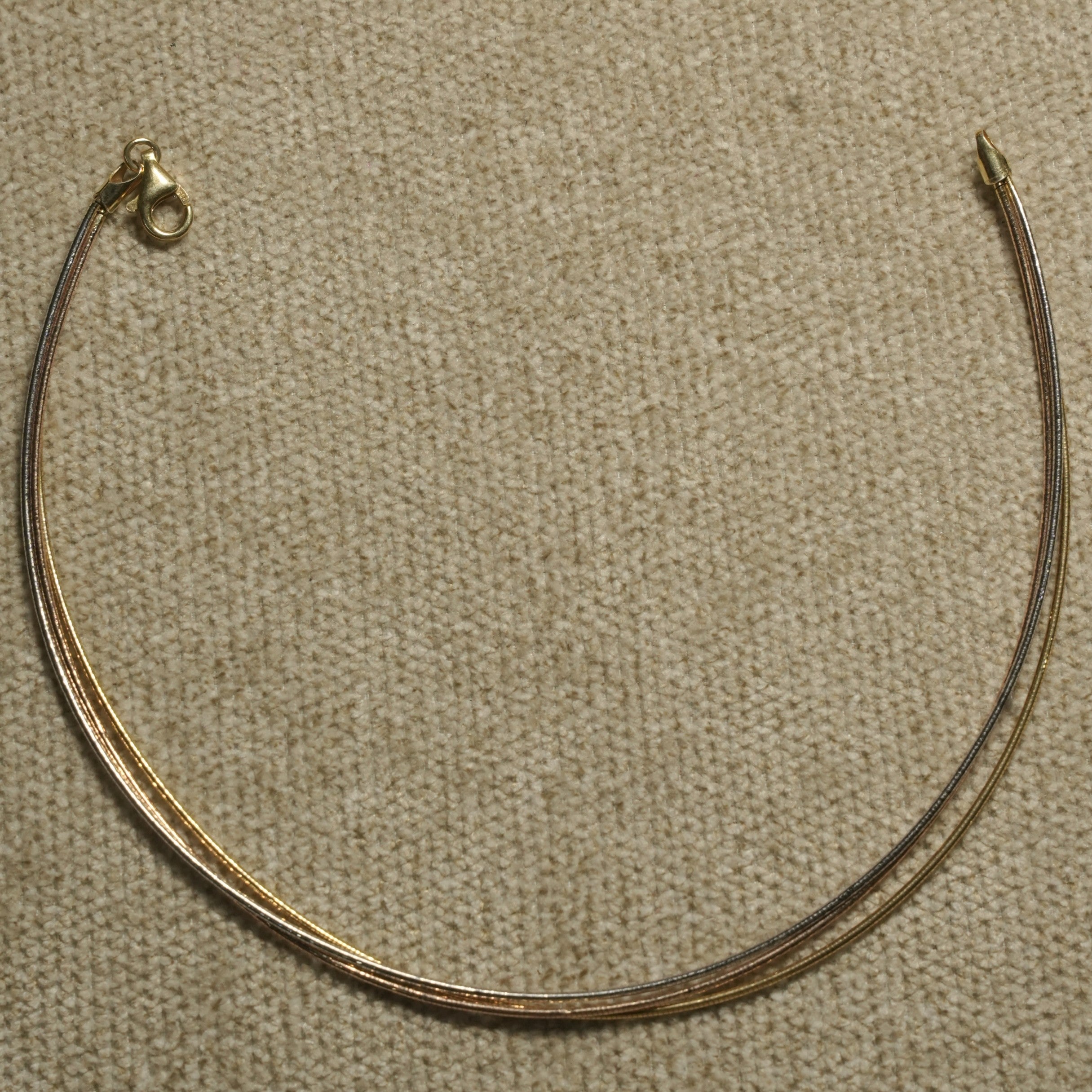 Sterling silver anklet with gold-tone and rose gold-tone strands photographed from above on textured cloth.