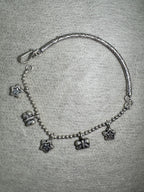 The sterling silver anklet laid in an open curve, showing the S-hook closure and the alternating star and butterfly charms.