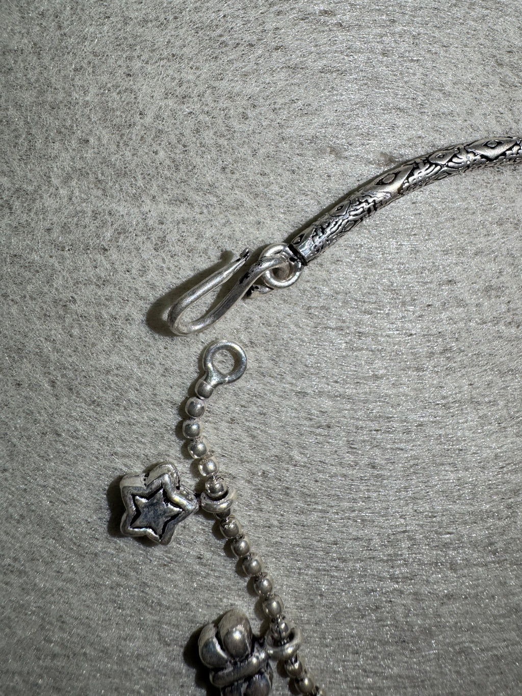 Close view of the S-hook and ring closure on the sterling silver anklet, with a star charm on the ball chain alongside.