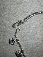 Close view of the S-hook and ring closure on the sterling silver anklet, with a star charm on the ball chain alongside.