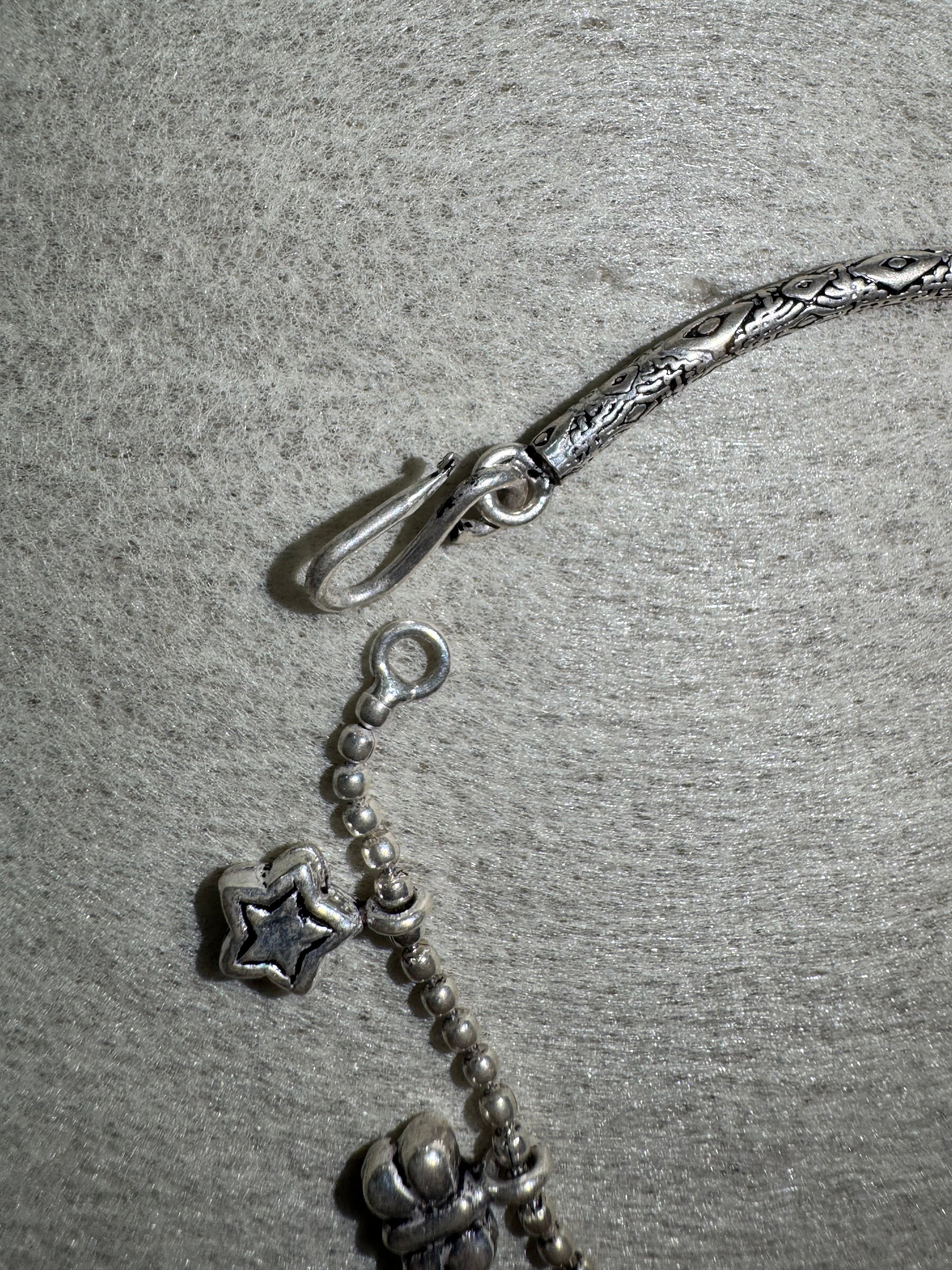 Close view of the S-hook and ring closure on the sterling silver anklet, with a star charm on the ball chain alongside.