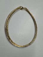 Multi-strand sterling silver snake chain anklet on a pale background, gold-tone and polished silver strands running together.