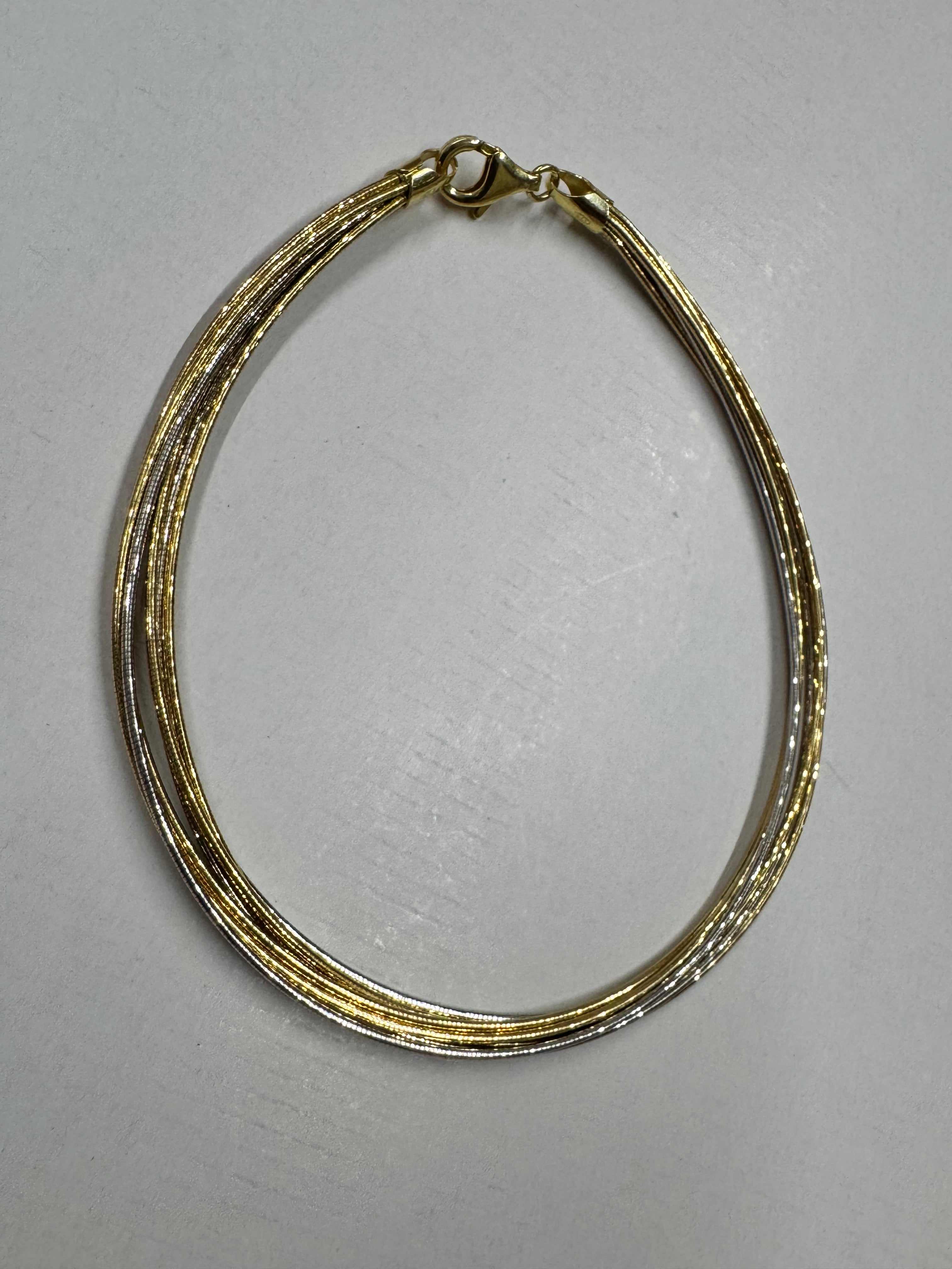 Multi-strand sterling silver snake chain anklet on a pale background, gold-tone and polished silver strands running together.
