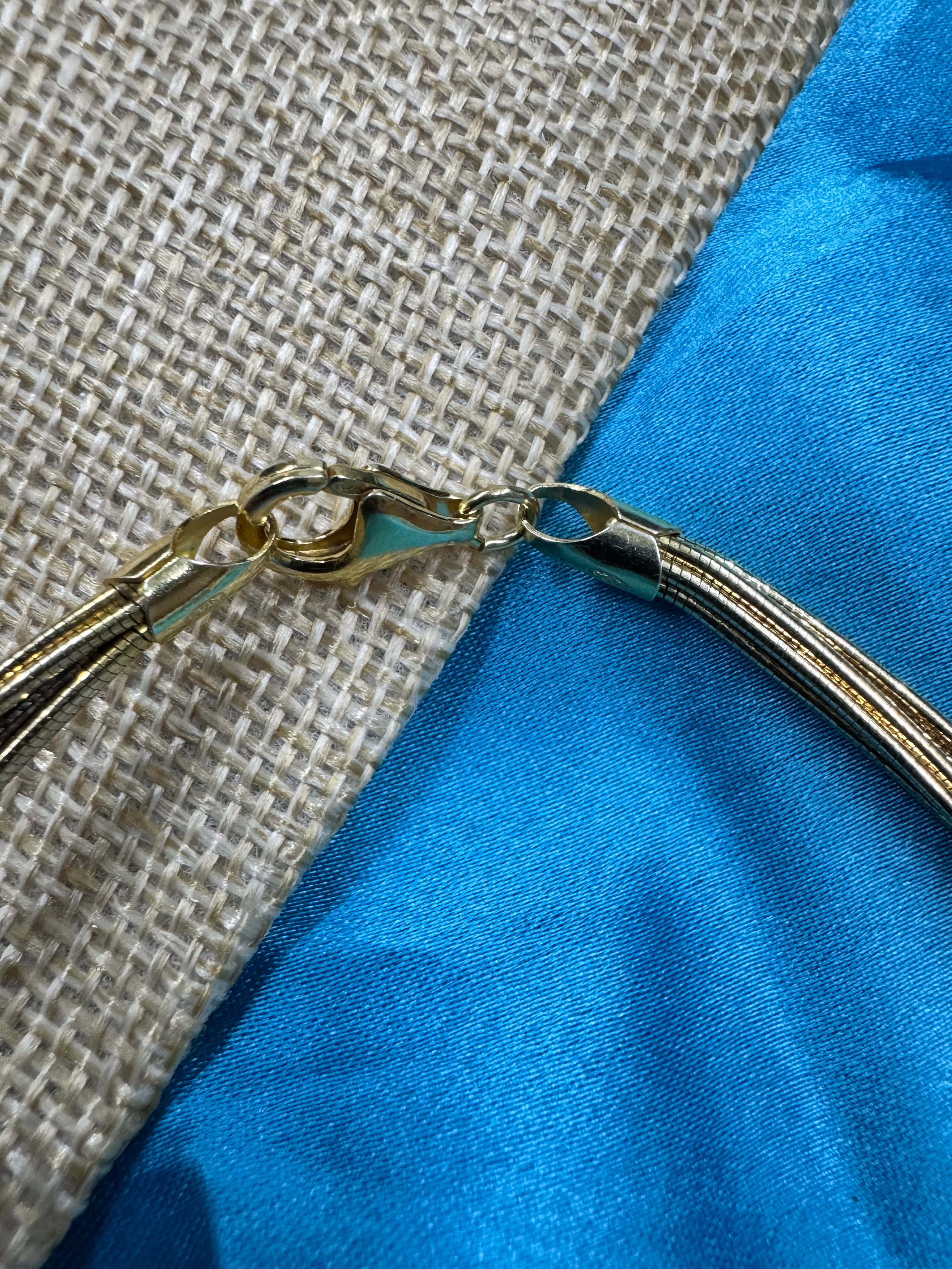 Close view of the lobster clasp and tapered end cap on the sterling silver anklet, against woven jute and blue satin.