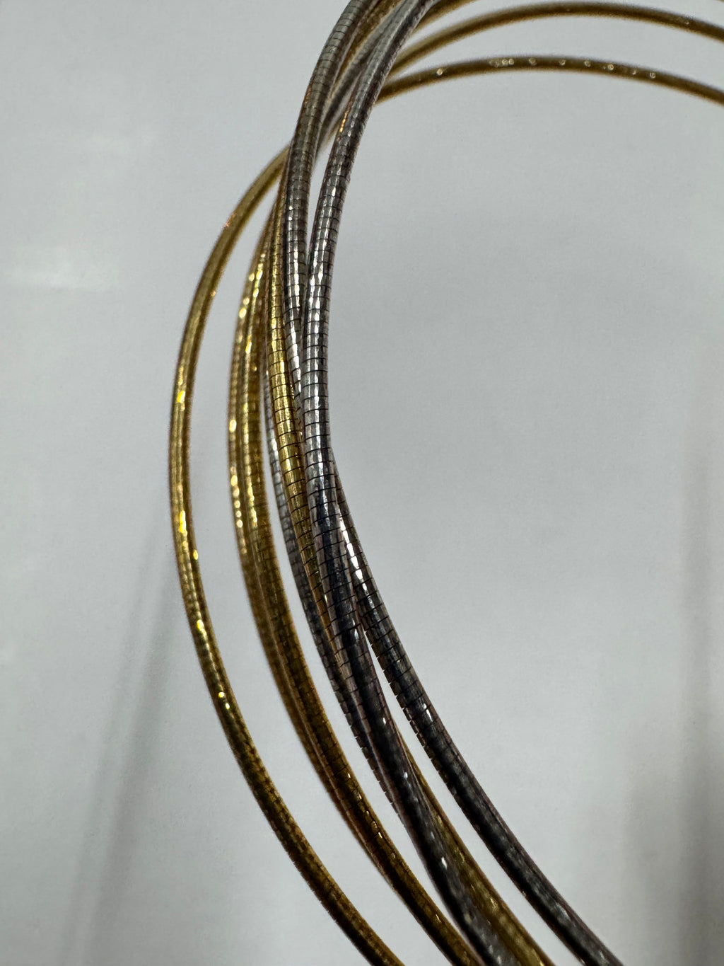 Macro view of the anklet's snake chains, showing the gold-tone and polished silver strands side by side.