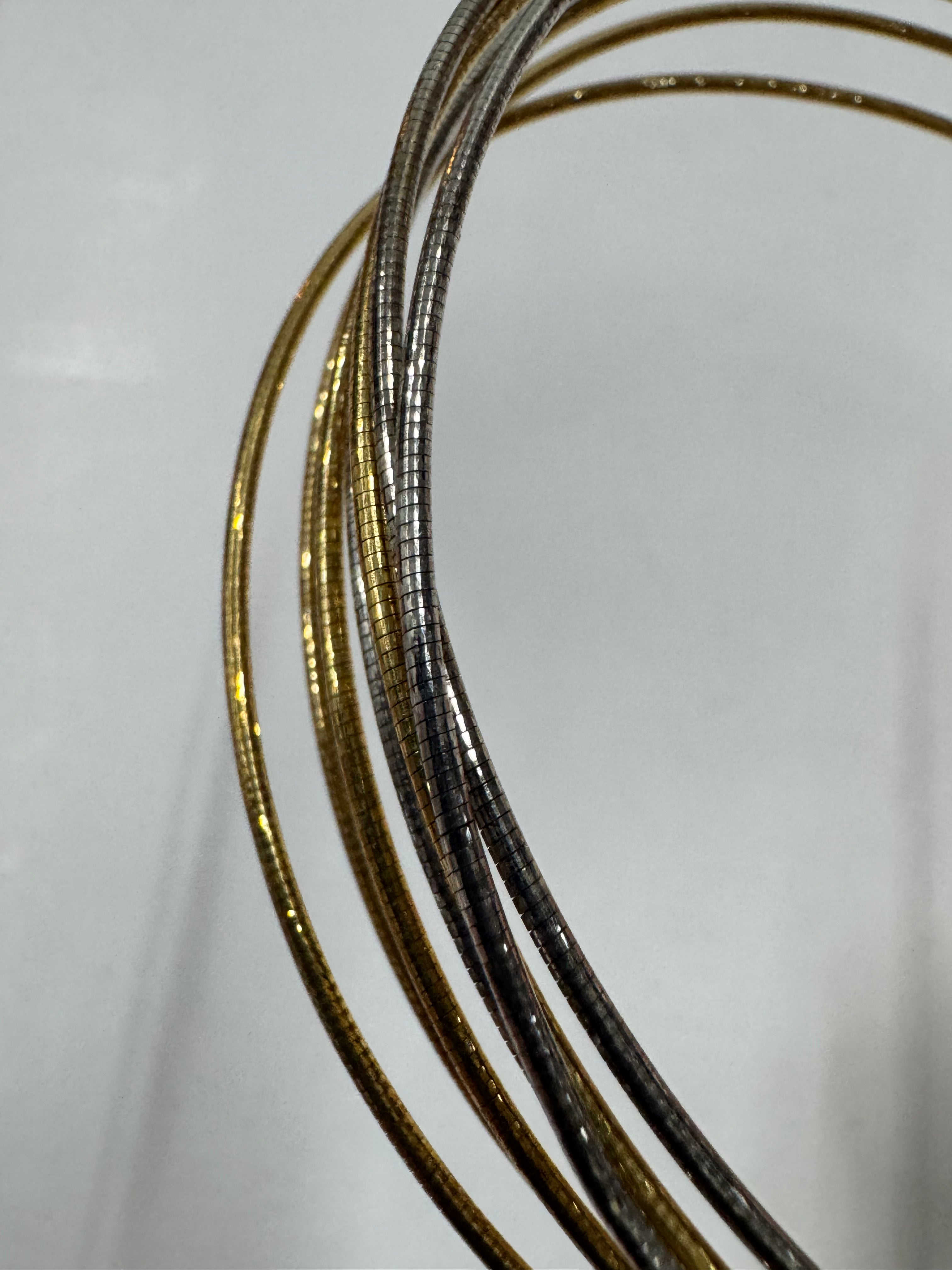 Macro view of the anklet's snake chains, showing the gold-tone and polished silver strands side by side.