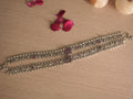 Pair of silver payal with pink and green stone flower clusters, laid side by side on a pale wooden surface with rose petals.