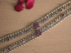 Close view of the two silver payal, showing the woven band and the flower clusters with deep pink petal shaped stones.