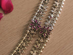 Angled close up of a flower cluster on the silver payal, with deep pink petal stones around a green centre.