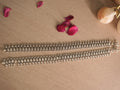 Pair of broad oxidised silver payal laid side by side, showing coin disc rows and textured marquise links.