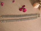 Pair of broad oxidised silver payal laid side by side, showing coin disc rows and textured marquise links.