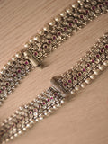 Pair of wide silver payal with rows of deep pink glass stones, laid flat on a pale background.