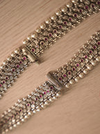 Pair of wide silver payal with rows of deep pink glass stones, laid flat on a pale background.