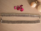Close view of the payal lattice, with round deep pink glass stones set between silver flowers.
