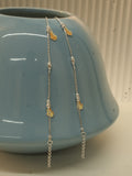 Pair of silver payal with yellow and orange enamel butterflies, draped over a blue ceramic vase.