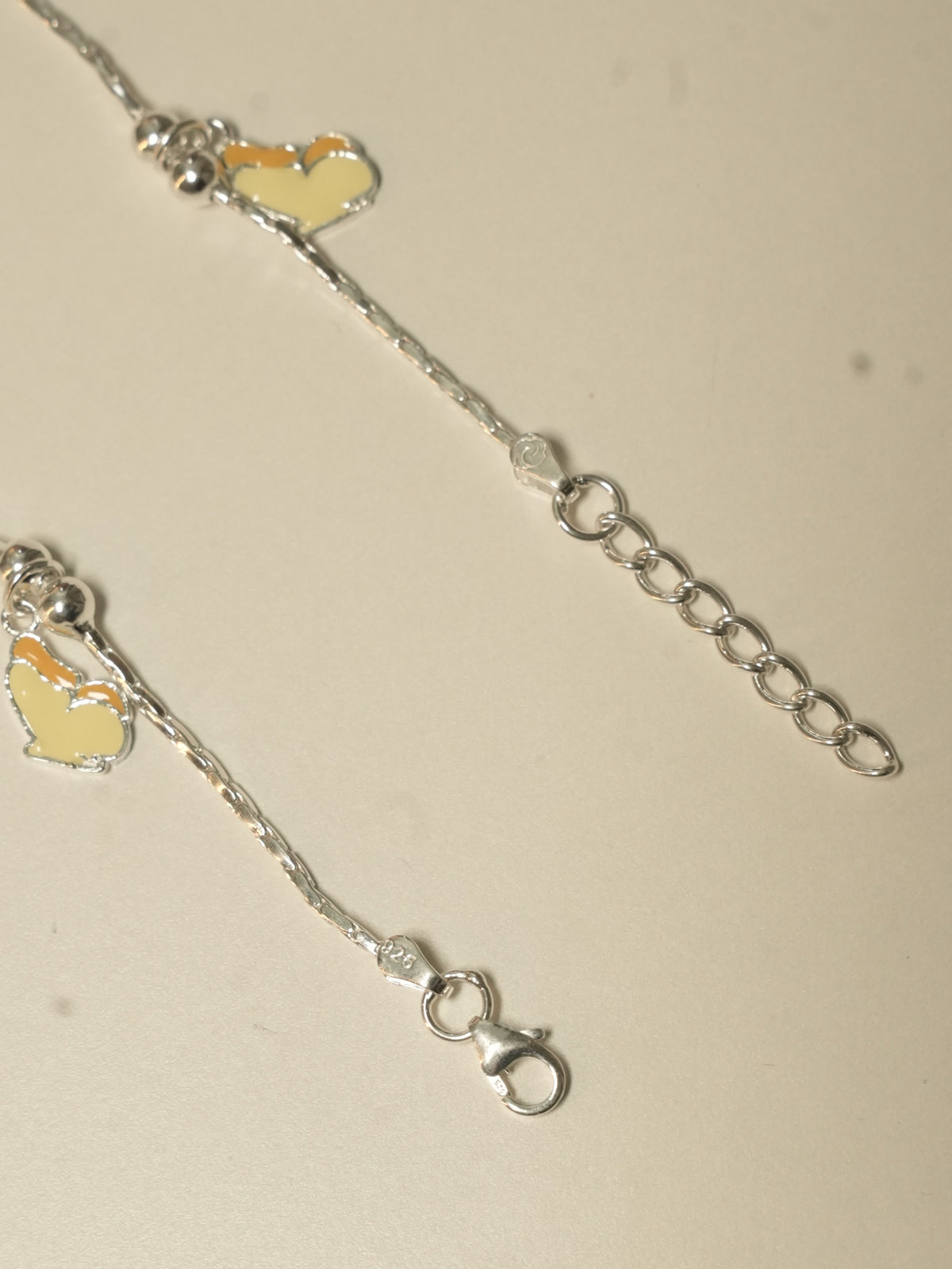 Close view of the lobster clasp, the extender chain and two enamel butterflies.