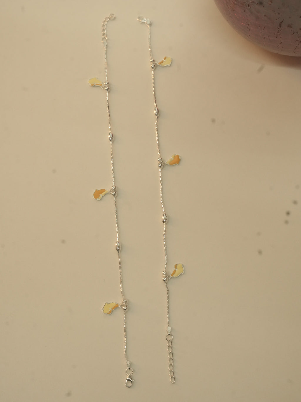 The pair of silver butterfly payal laid out full length, showing the spacing of the butterflies.