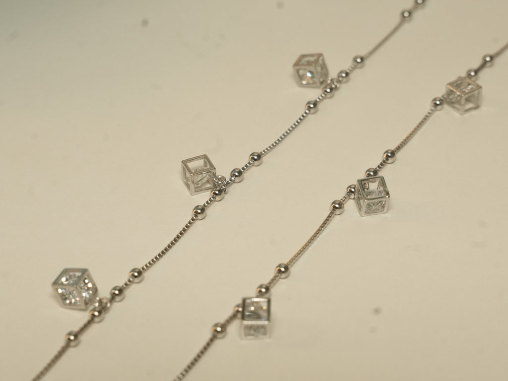 Pair of silver payal with open cube charms, each holding an American Diamond, on a box chain with bead stations.
