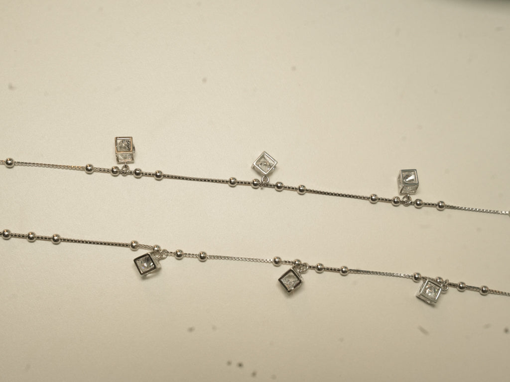 The pair of cube charm payal laid out side by side, showing three cubes on each.
