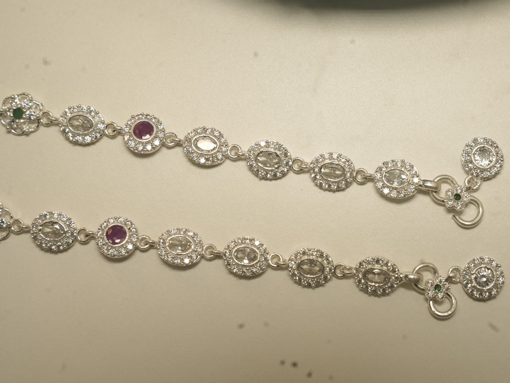 Clasp end of the oval halo payal, showing the hook, the flower link with a green centre and the round halo drop.