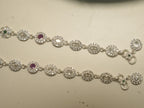 Clasp end of the oval halo payal, showing the hook, the flower link with a green centre and the round halo drop.