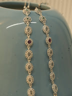 The oval halo payal draped over a blue ceramic vase, seen from the flower link end.