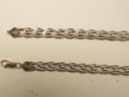 Pair of rose gold plated braided herringbone silver payal laid side by side, showing the lobster clasp and the stamped end caps.