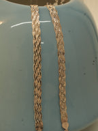 Close view of the rose gold plated braided payal on a blue vase, showing how the strands cross.