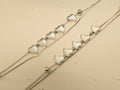 Close view of five polished silver hearts in a row on each of a pair of double strand payal.