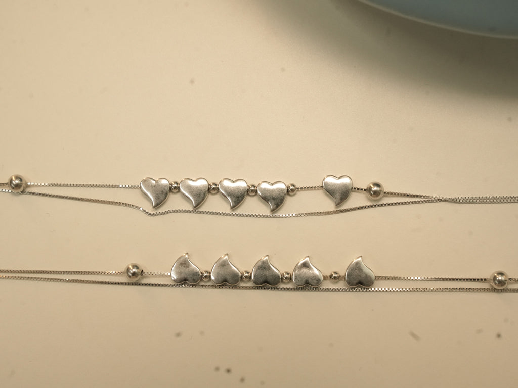 Pair of sterling silver payal, each with five hearts between bead stations on a double strand of box chain.